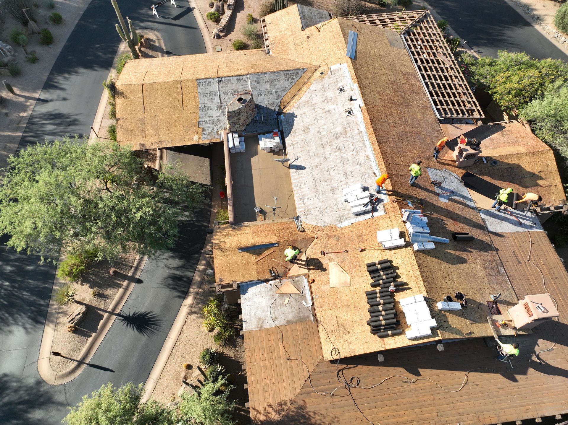 An aerial view of a house under construction with workers on the roof.