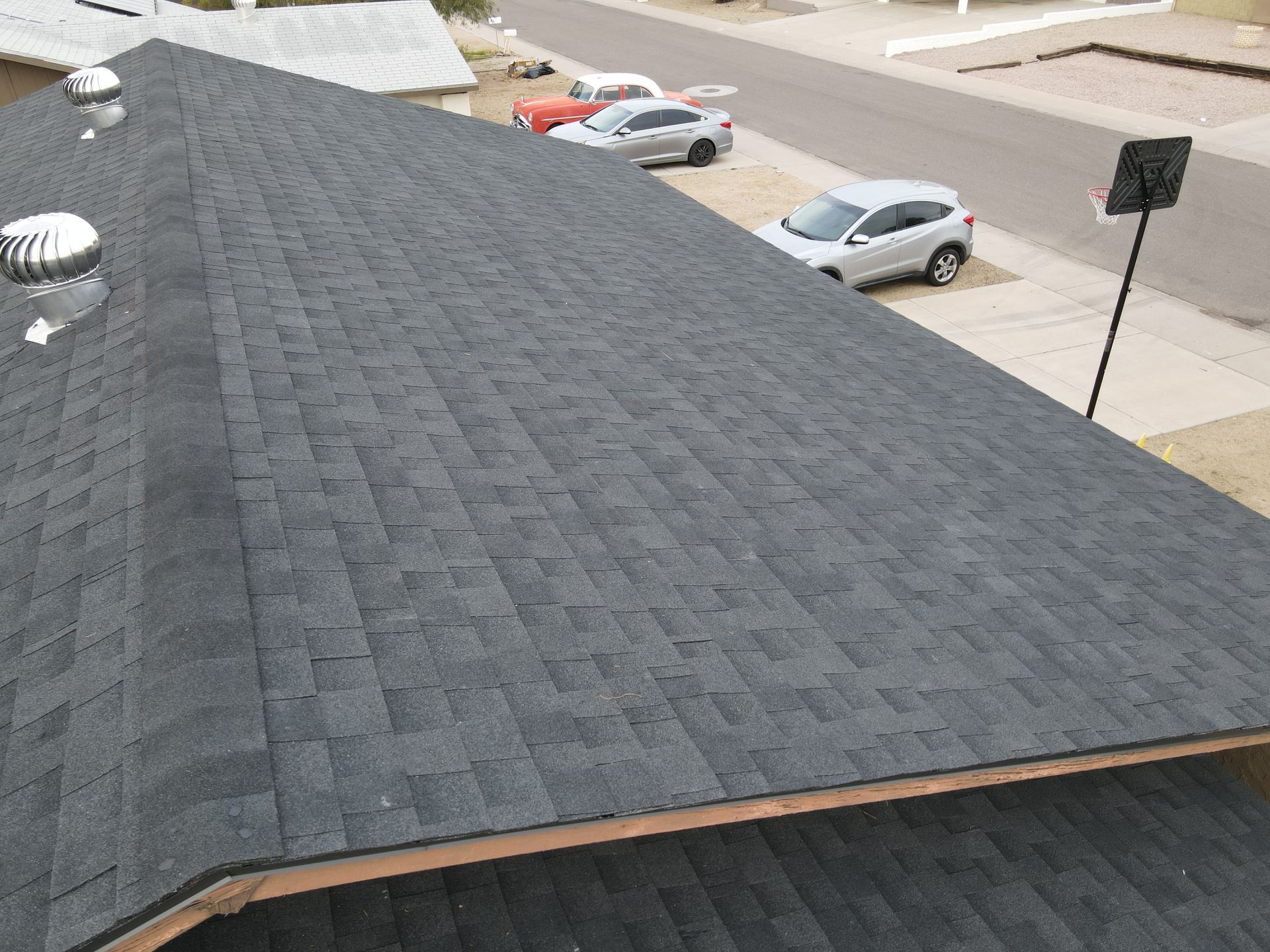 An aerial view of a roof with cars parked on the side of the road.