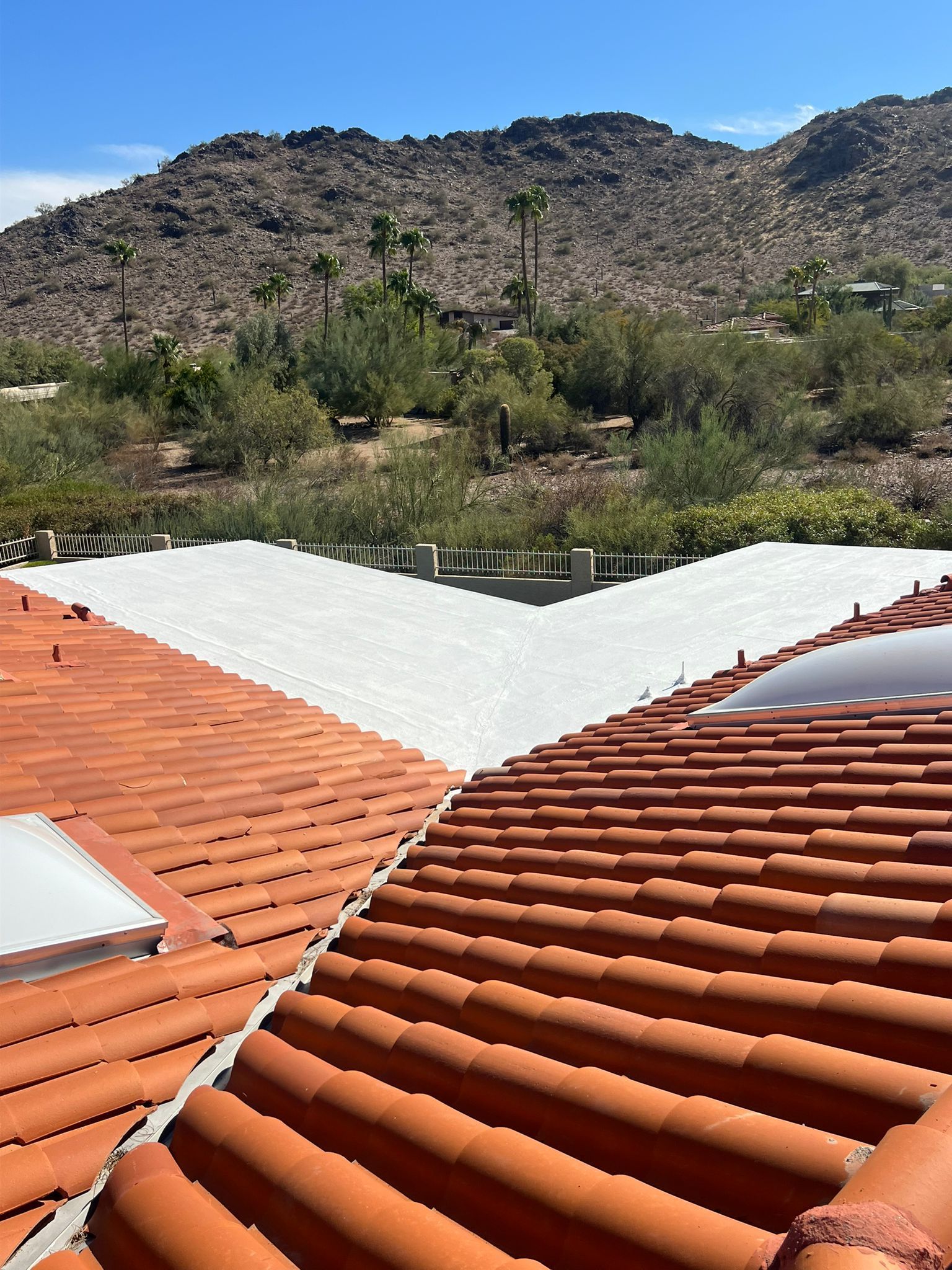 A red tile roof with a white roof and mountains in the background.