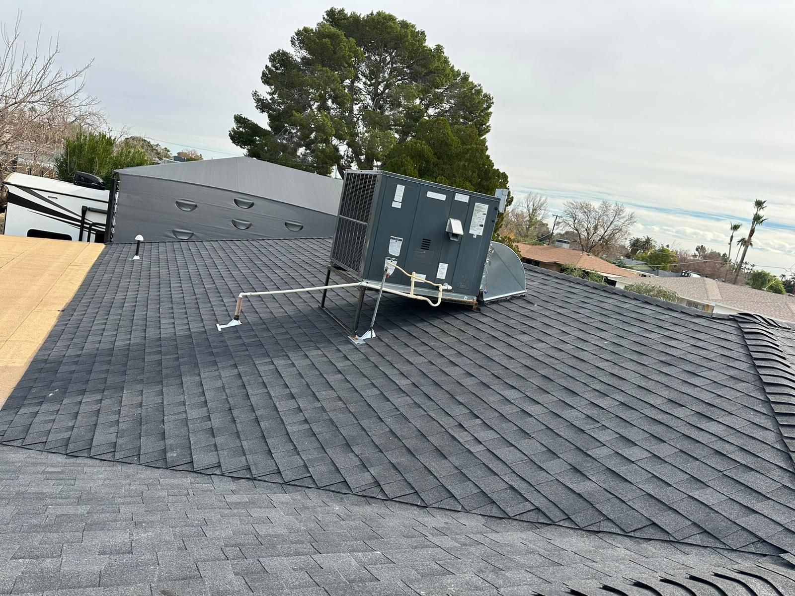A roof with a box on top of it and a tree in the background.