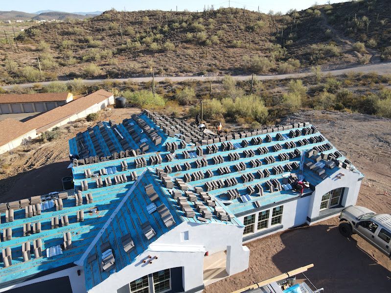 An aerial view of a house under construction with a blue roof.