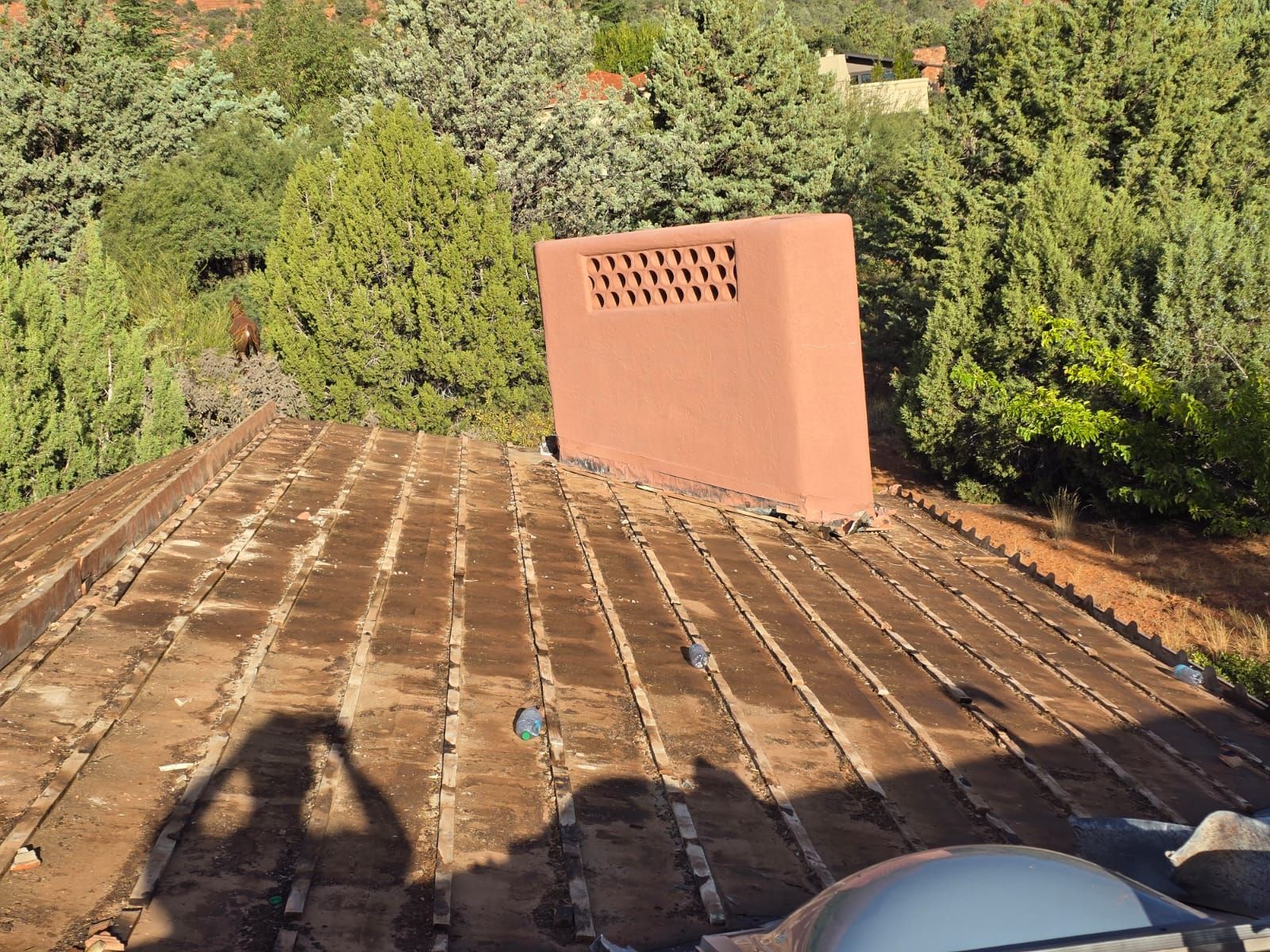 A roof with a chimney on it and a shadow of a person on it.