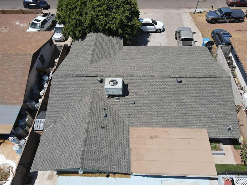 An aerial view of a roof of a house with cars parked in front of it.