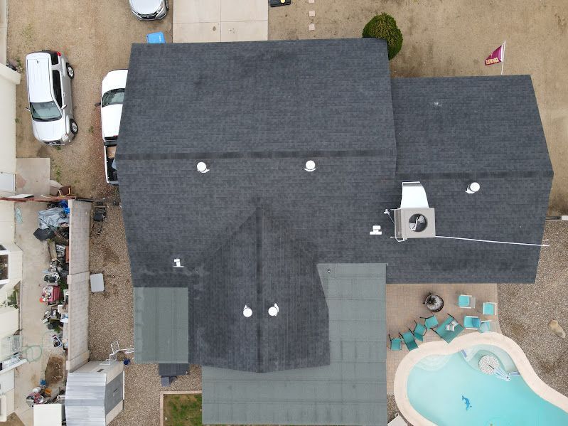 An aerial view of a house with a pool and a roof.