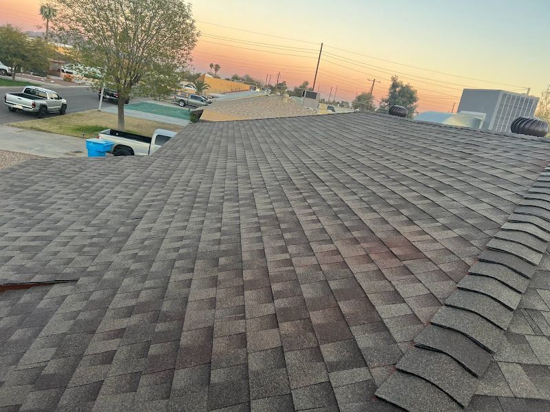 A roof with a lot of shingles on it and a sunset in the background.