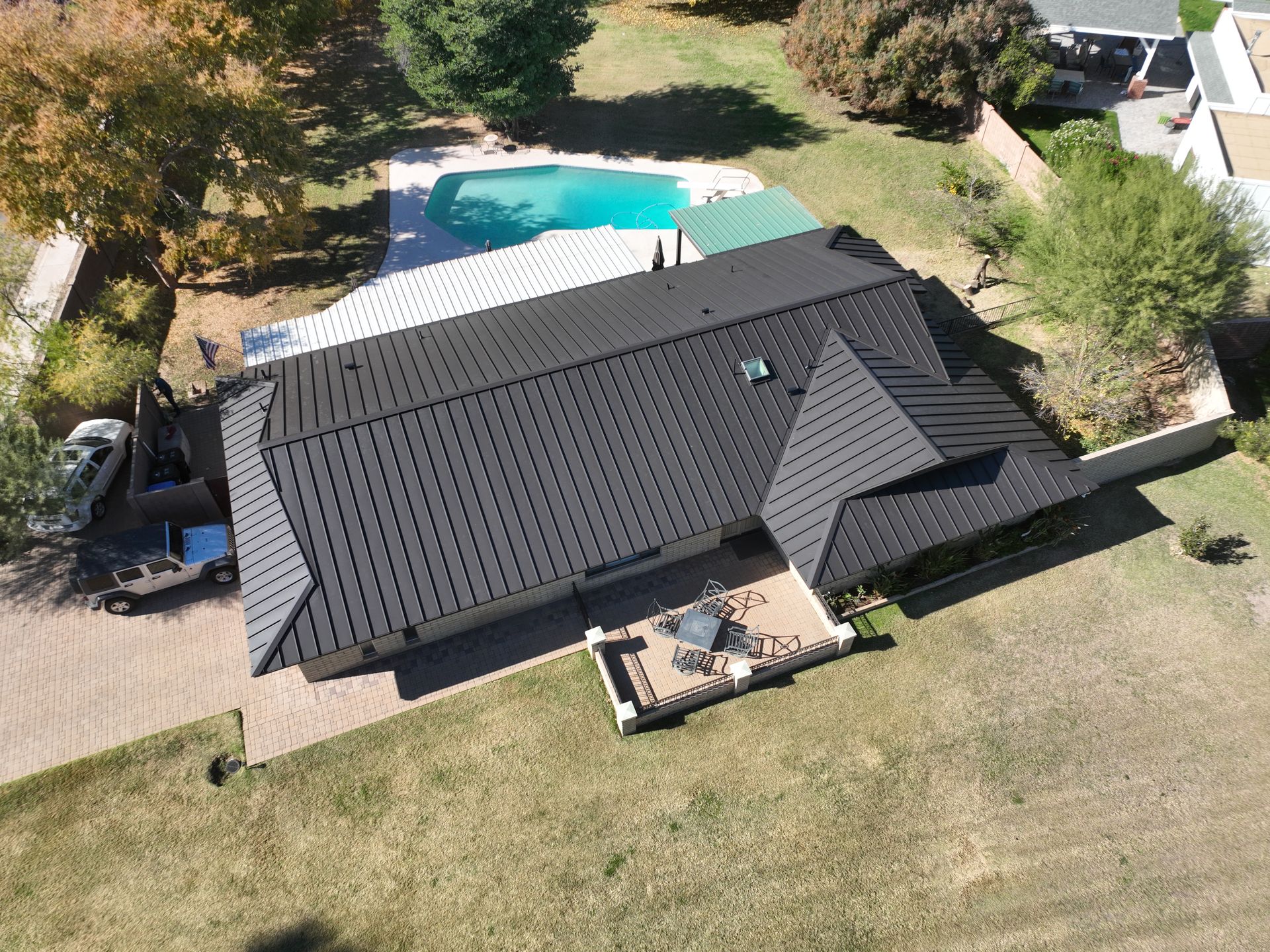 An aerial view of a house with a black roof and a pool.