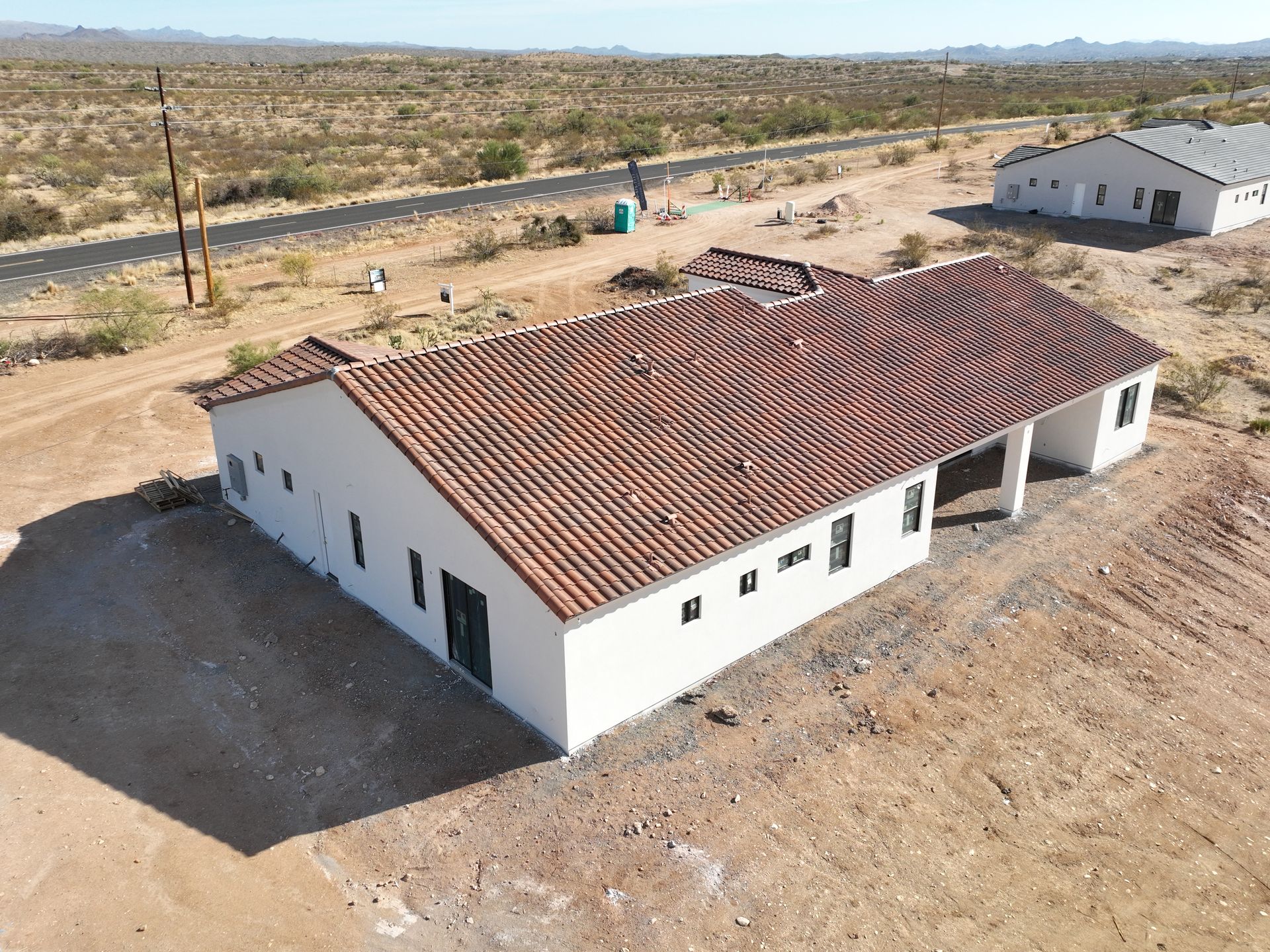 An aerial view of a white building with a tiled roof in the desert.