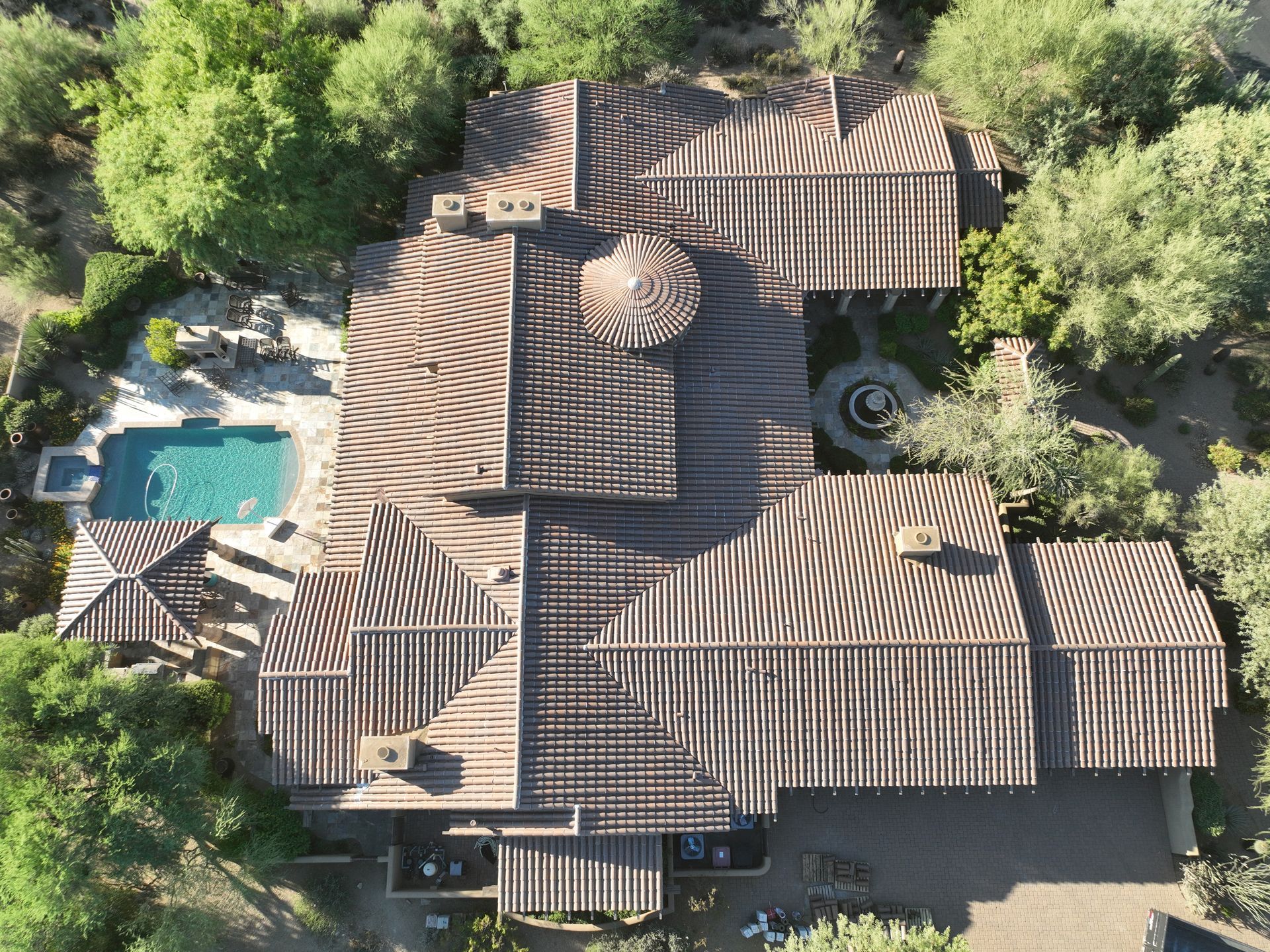 An aerial view of a large house with a pool surrounded by trees.