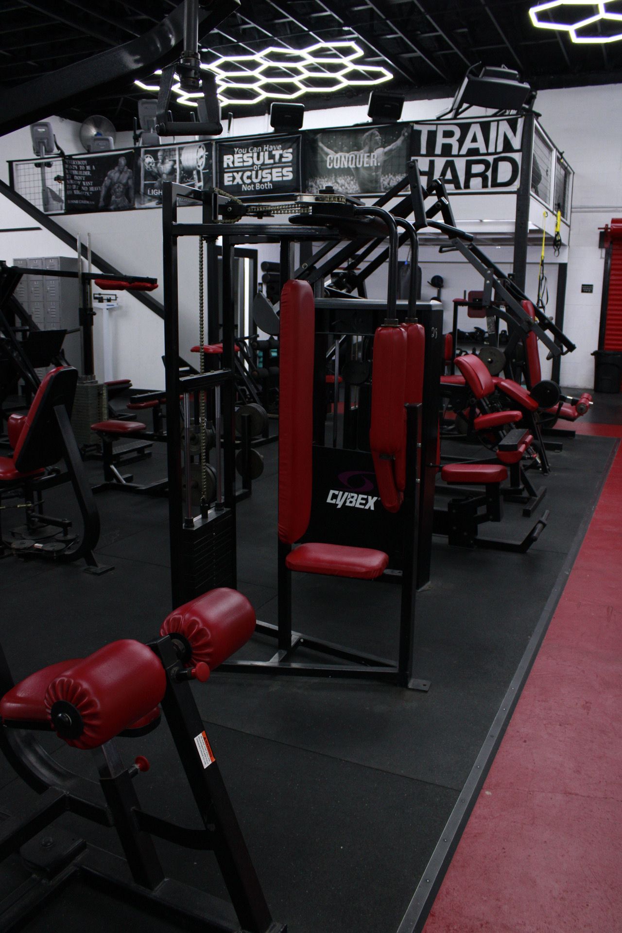 A gym filled with lots of exercise equipment and a sign that says train hard.
