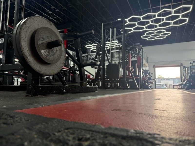 A large barbell is sitting in the middle of a gym.