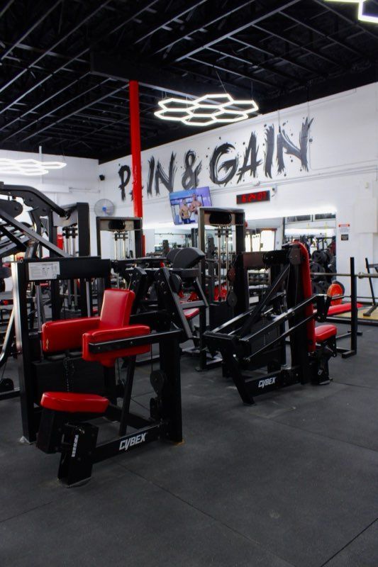 A gym with a sign on the wall that says pain & gain