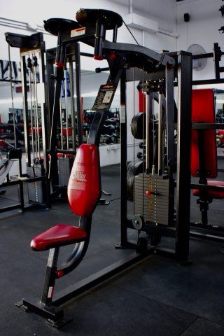 A red chair is sitting in a gym next to a machine.
