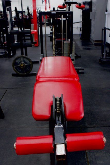A red bench in a gym with a lot of equipment