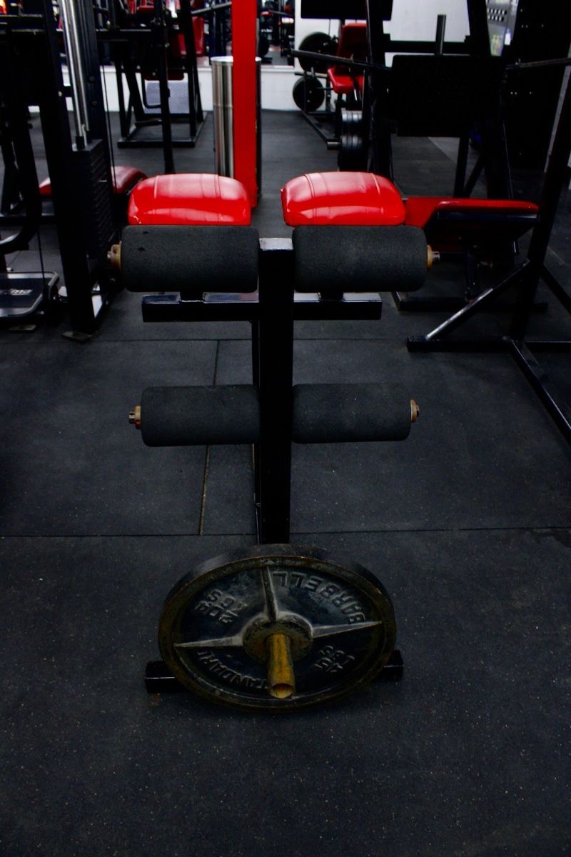 A gym with a bench and a weight plate on the floor