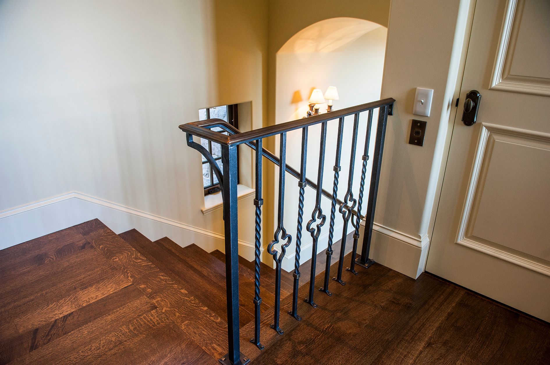 a wooden staircase with a wrought iron railing and a door