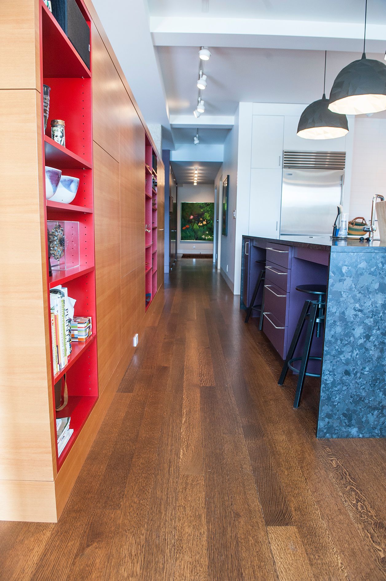 a long hallway leading to a kitchen with hardwood floors