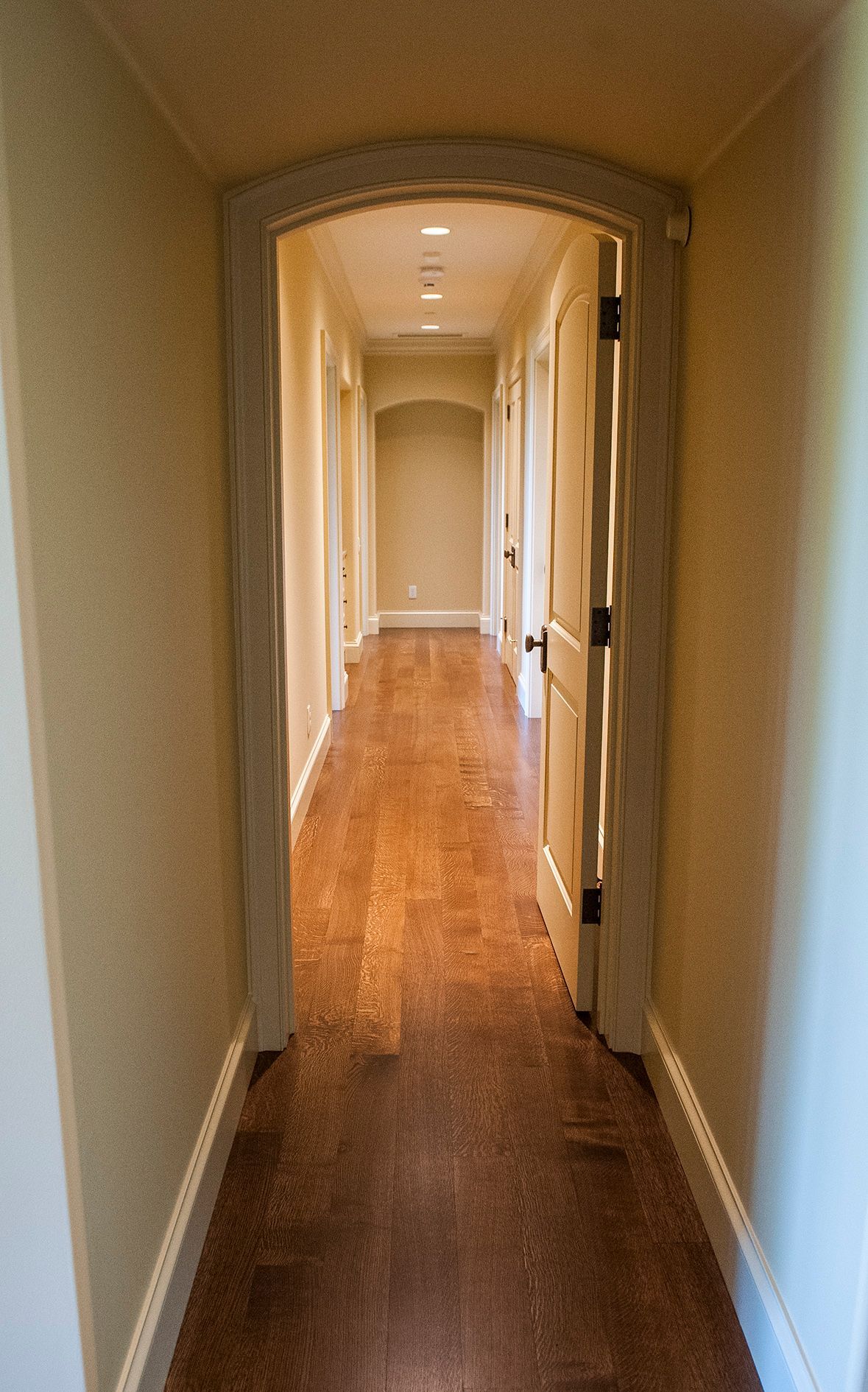 a long hallway with hardwood floors and a door that is open