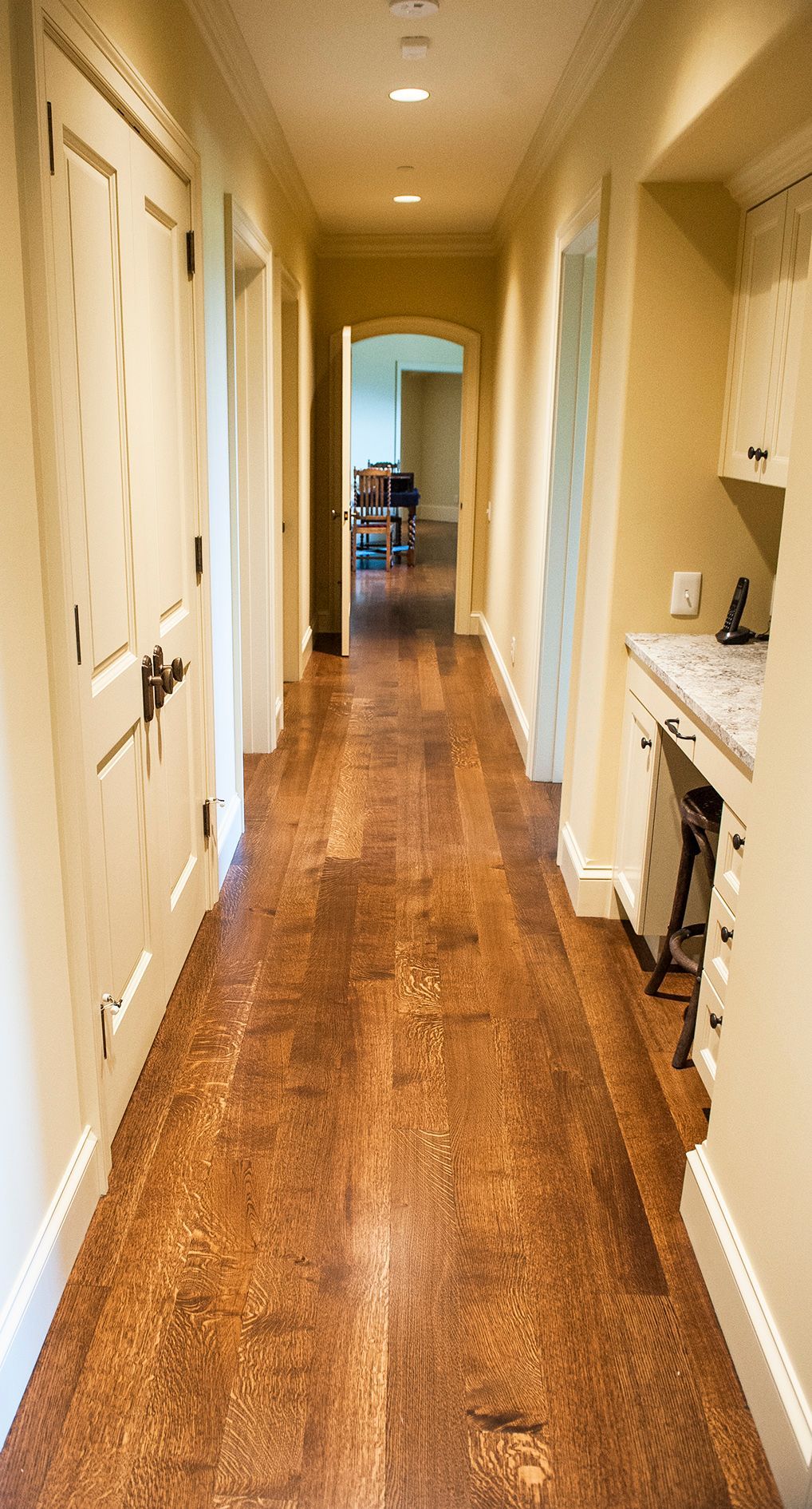 a long hallway with hardwood floors and white walls in a house