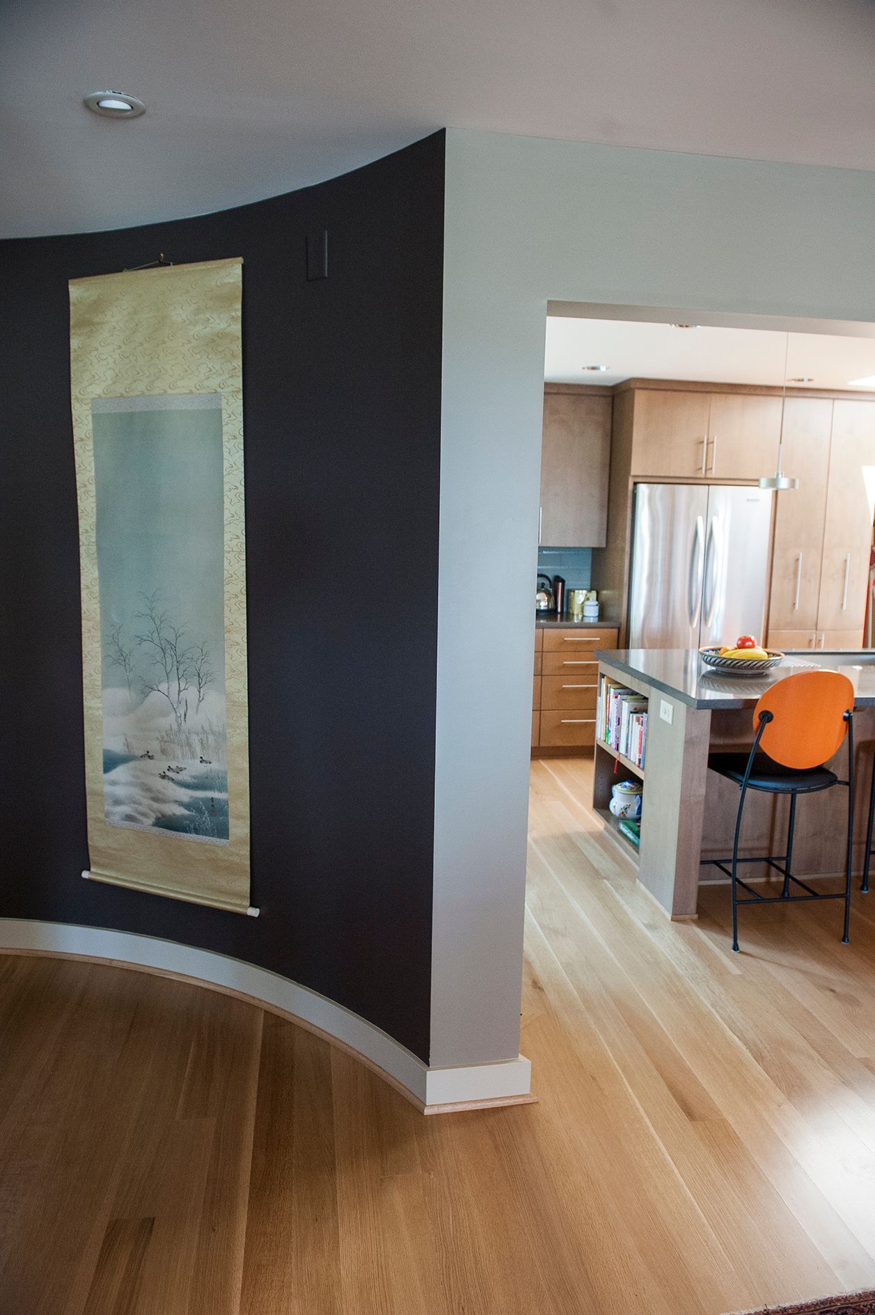 a kitchen with a curved wall and a large painting on the wall
