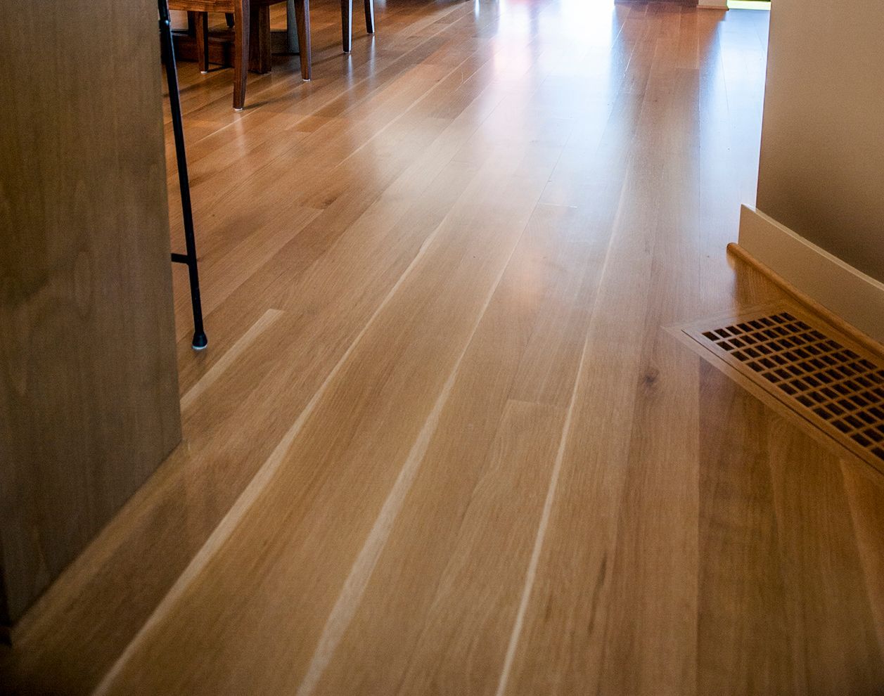 a wooden floor with a vent in the corner