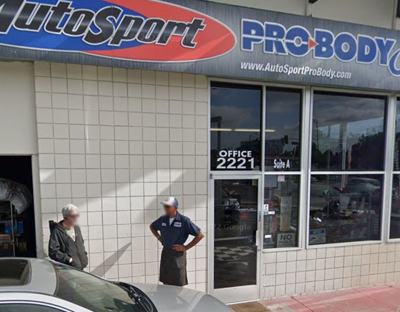 Two men are standing outside of a pro body shop