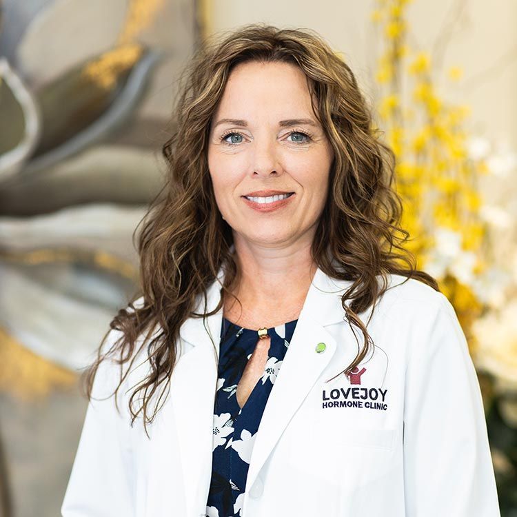 A woman in a white lab coat is smiling for the camera.