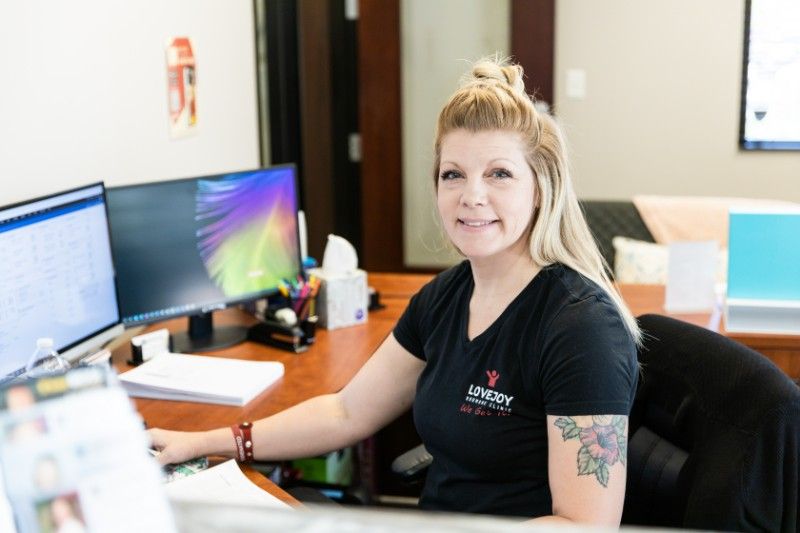 A woman is sitting at a desk in front of a computer.