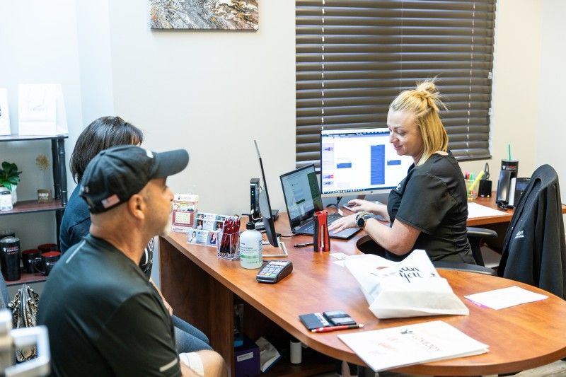A man and a woman are sitting at a desk in front of a computer.