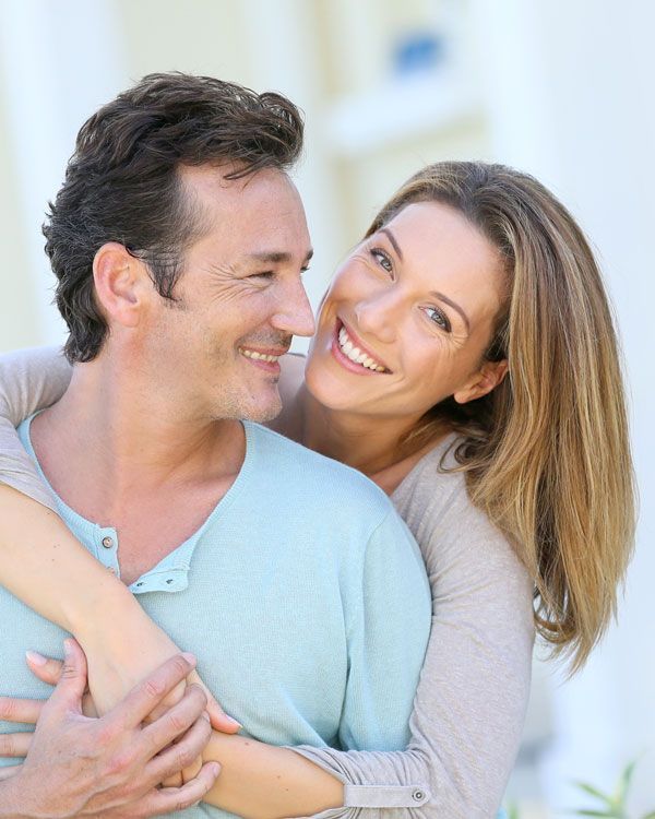 A woman is hugging a man and smiling at him