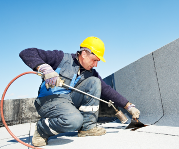 roofer installing roofing sheet with heating equipment