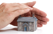 close up hands sheltering miniature house