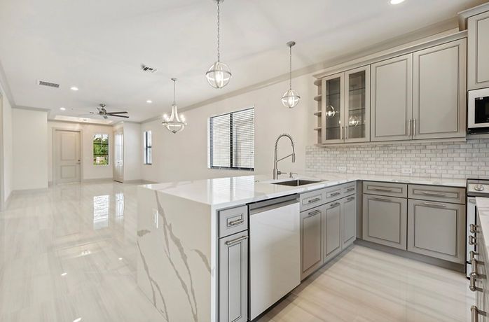 A kitchen in a new home with white cabinets and stainless steel appliances.