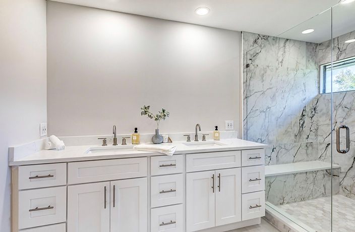 A bathroom with two sinks and a walk in shower.