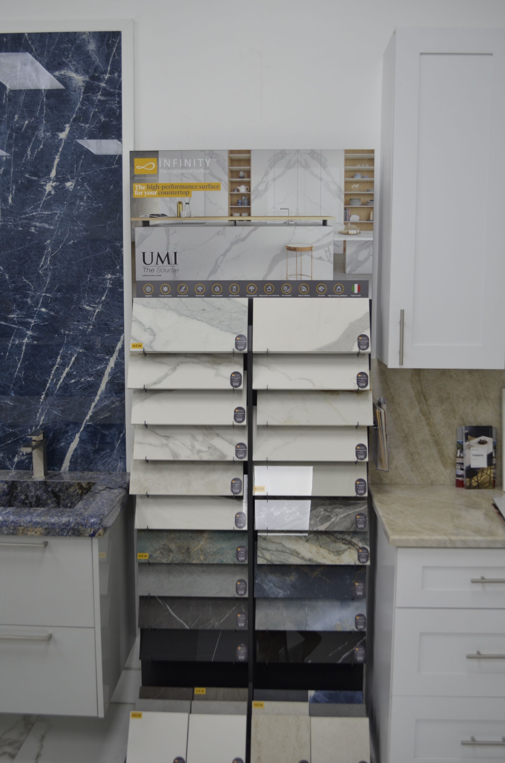 Tile samples displayed on a rack, with a countertop and cabinetry on either side, showroom.