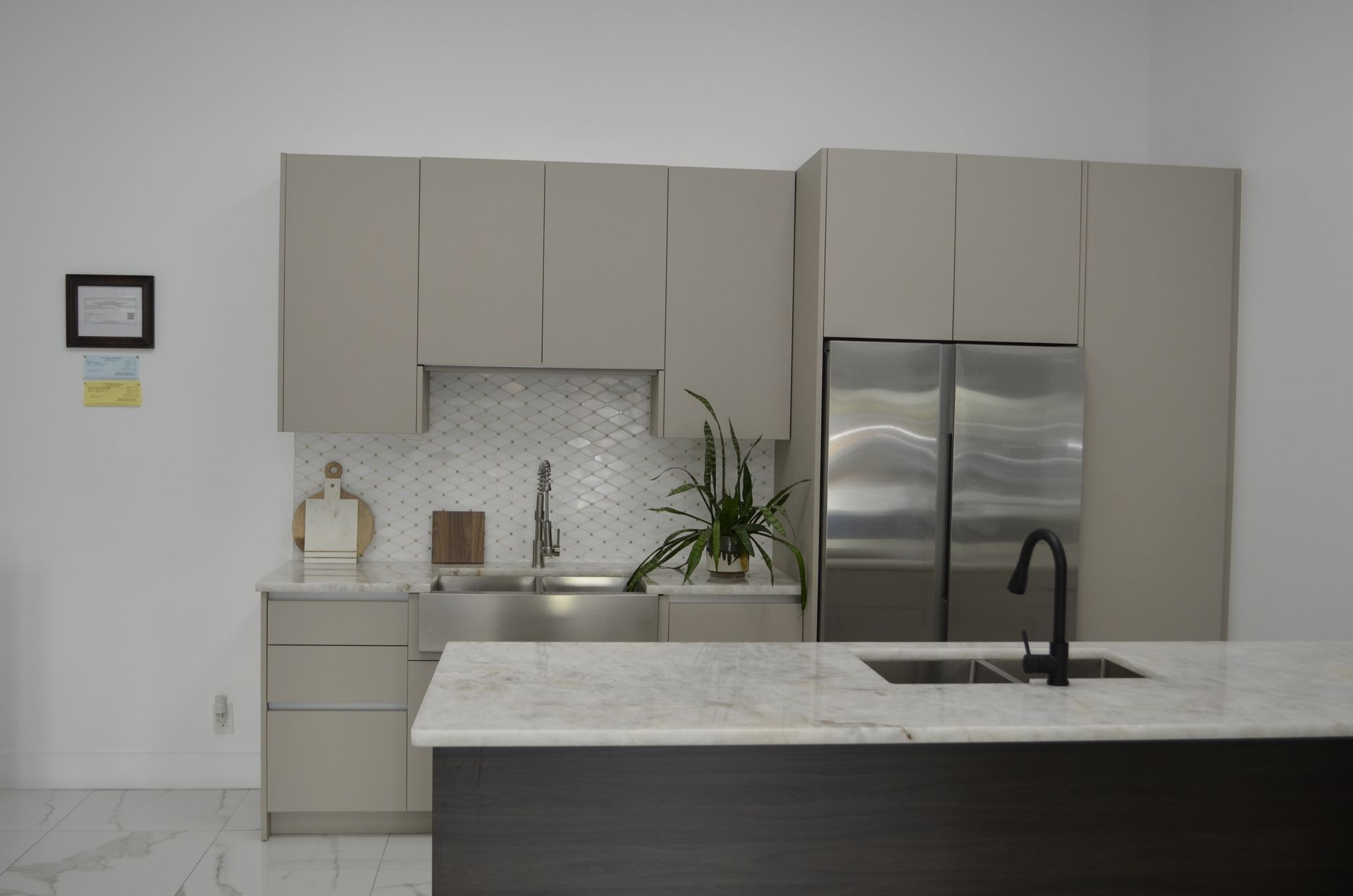 Modern kitchen with light grey cabinets, stainless steel appliances, and a marble countertop.