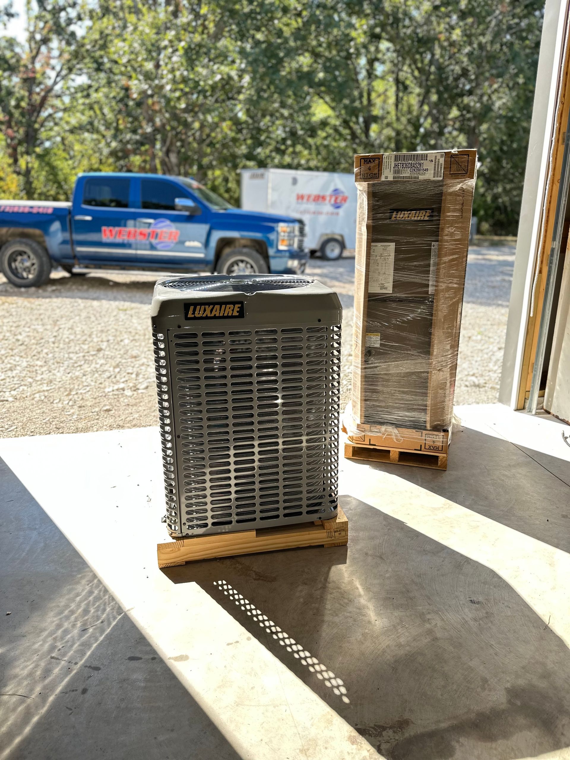 AC unit and new unit in packaging next to a blue truck.