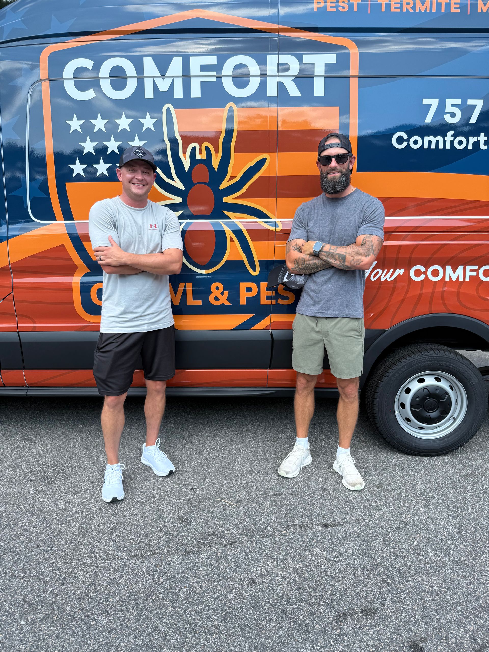 Two men stand in front of a Comfort pest control van. One man is smiling and the other has arms crossed.