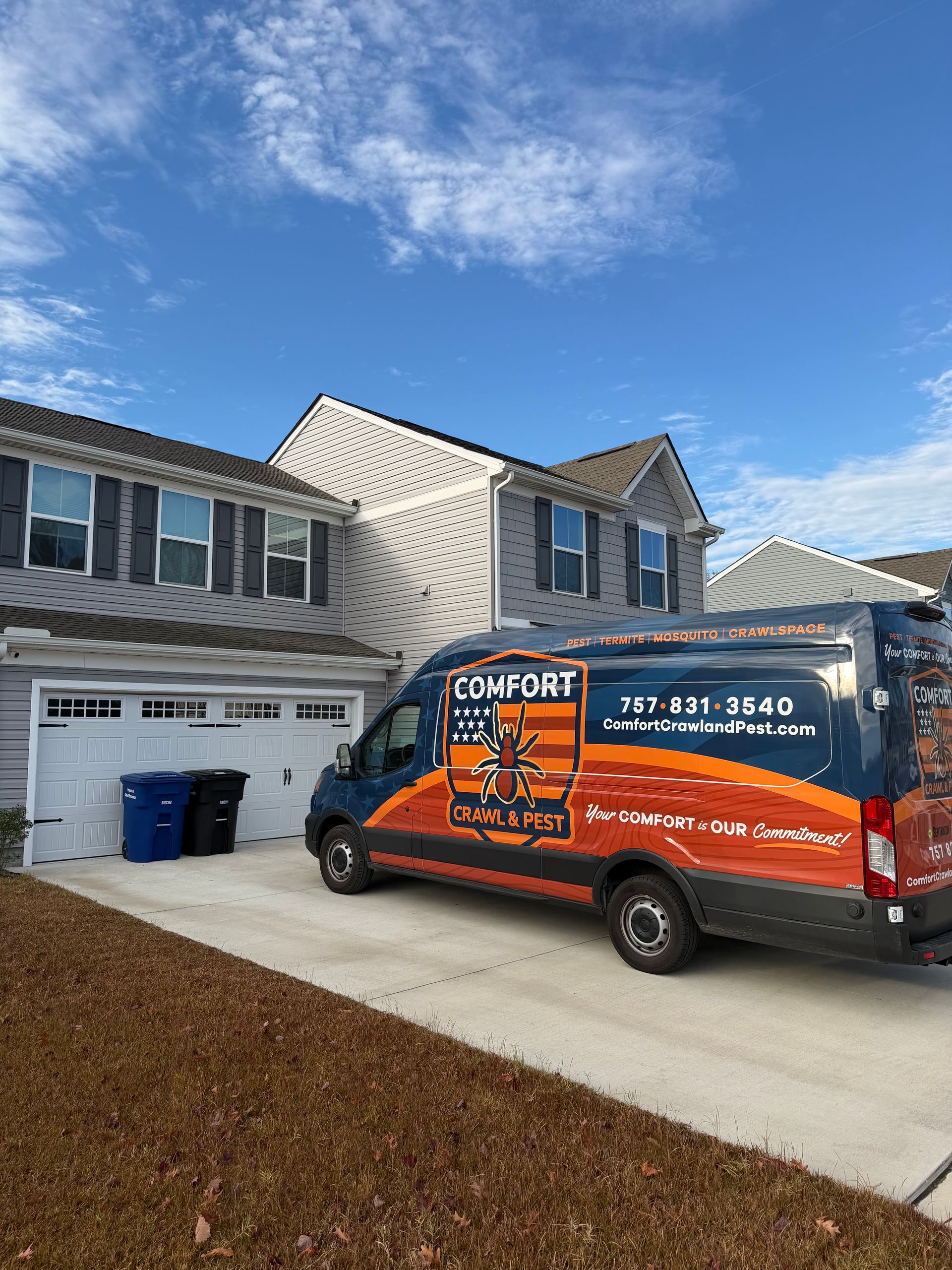 Blue and orange Comfort Tech van parked in a driveway in front of a gray two-story house.