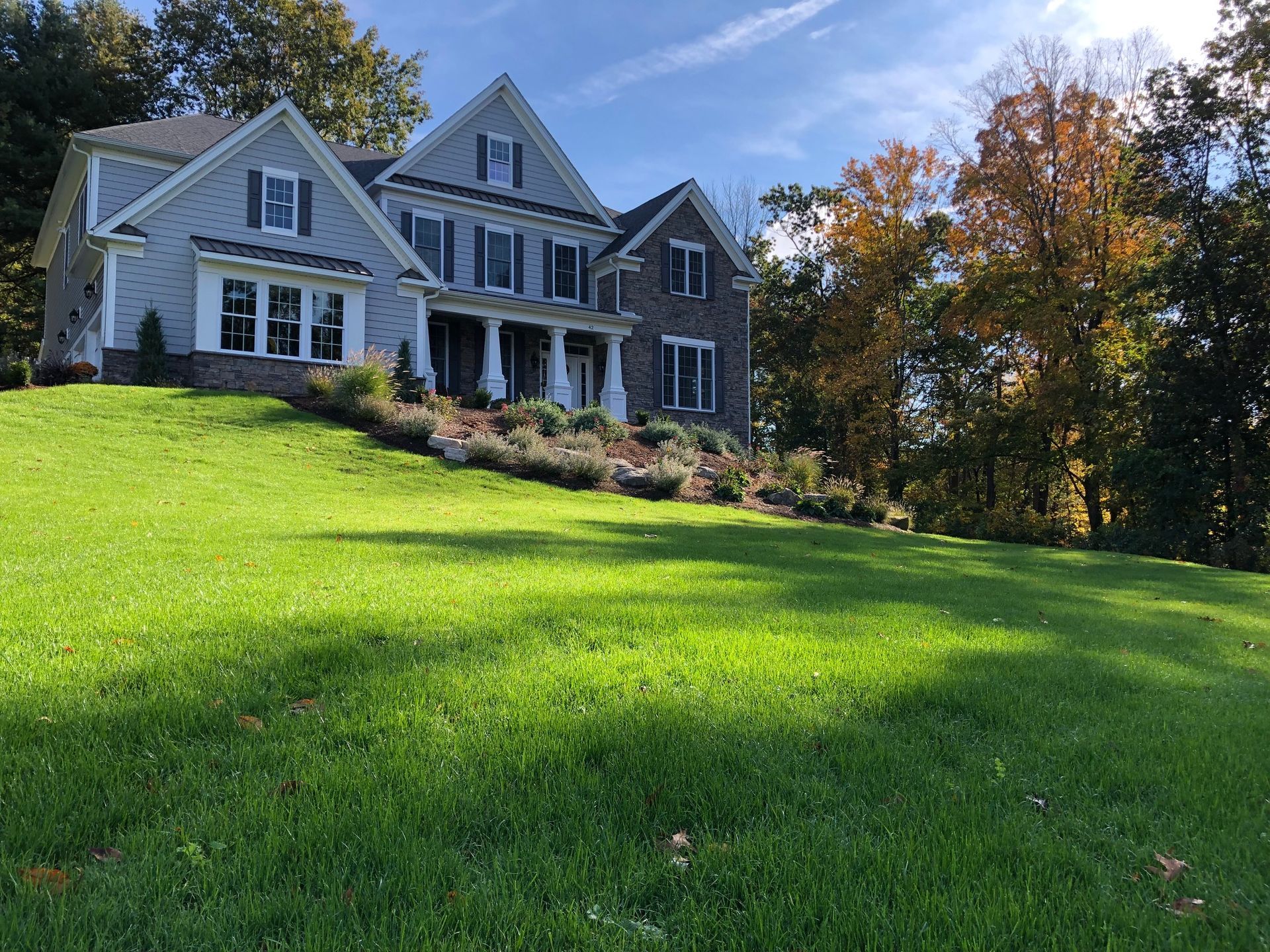 lush green grass in front of a huge beautiful gray house