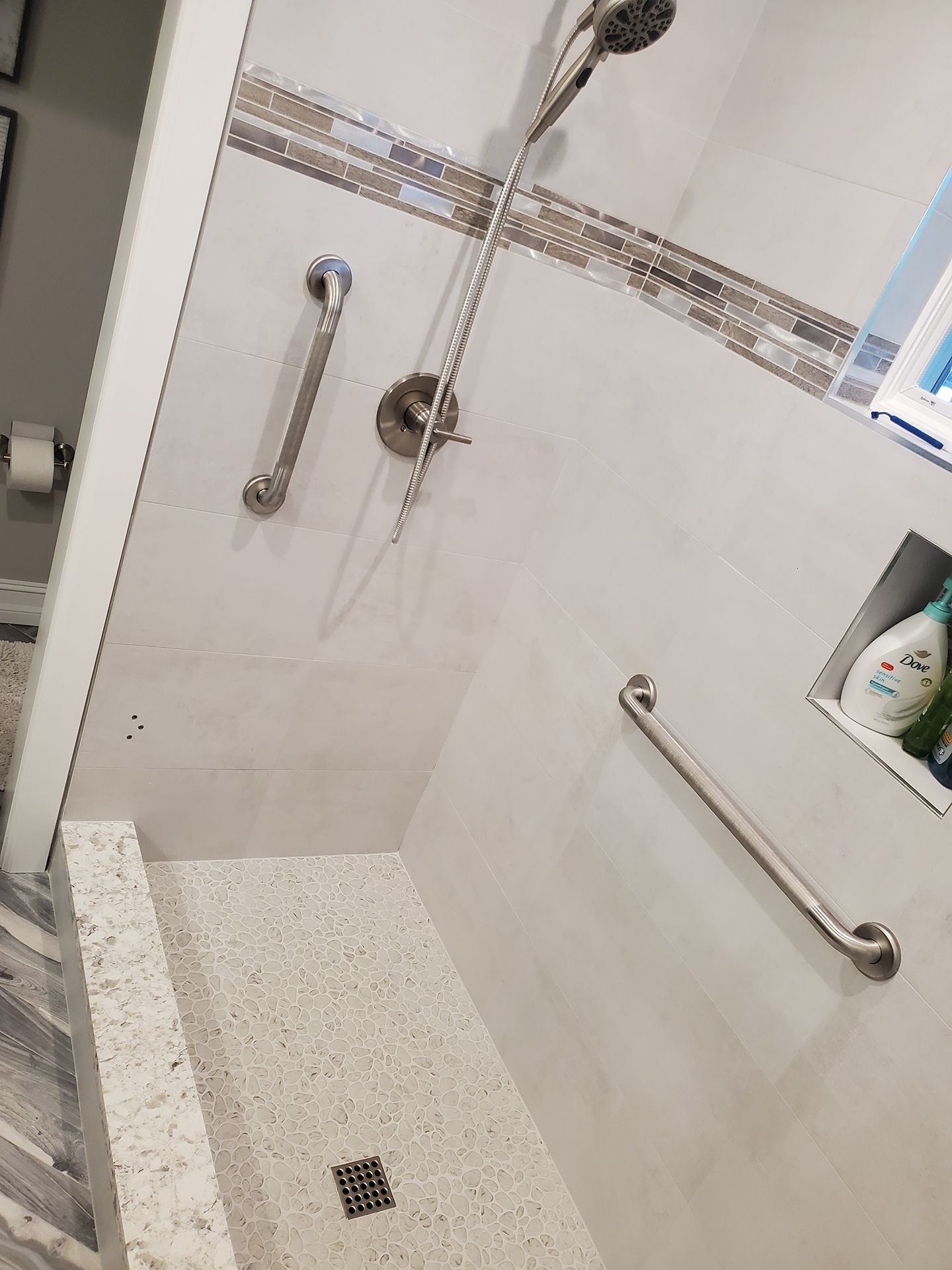 A bathroom with a walk in shower and a hand rail.