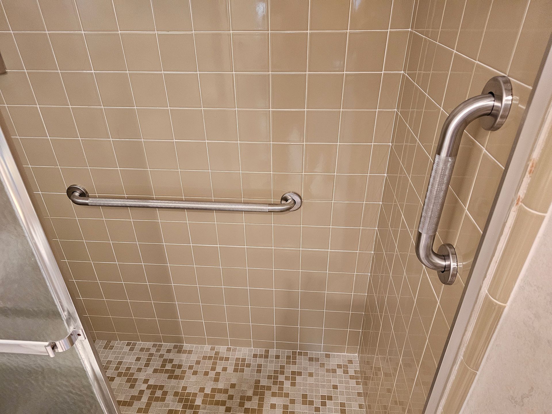 A shower with a stainless steel handle on the door.