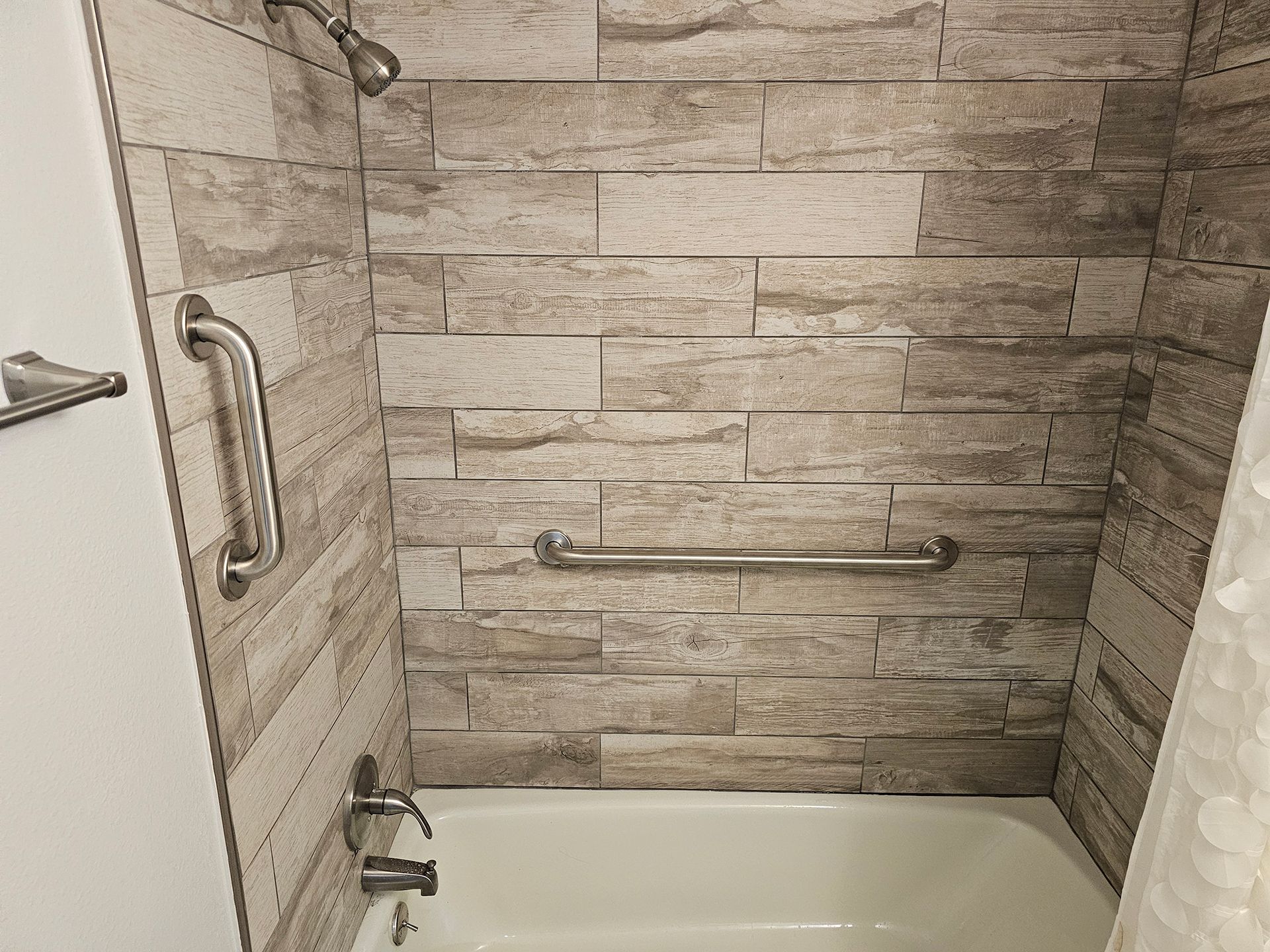 A bathroom with a bathtub and a shower with a brick wall.