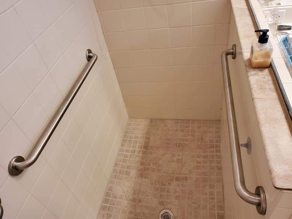 A bathroom with a walk in shower and stainless steel handles