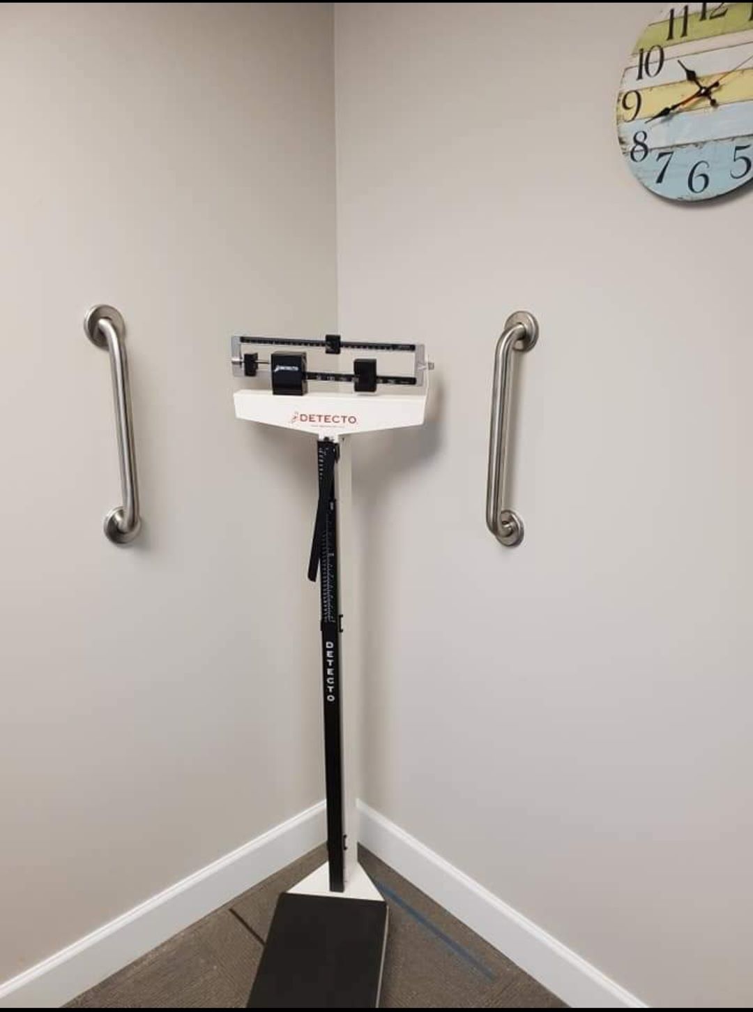 A bathroom with a scale and a clock on the wall