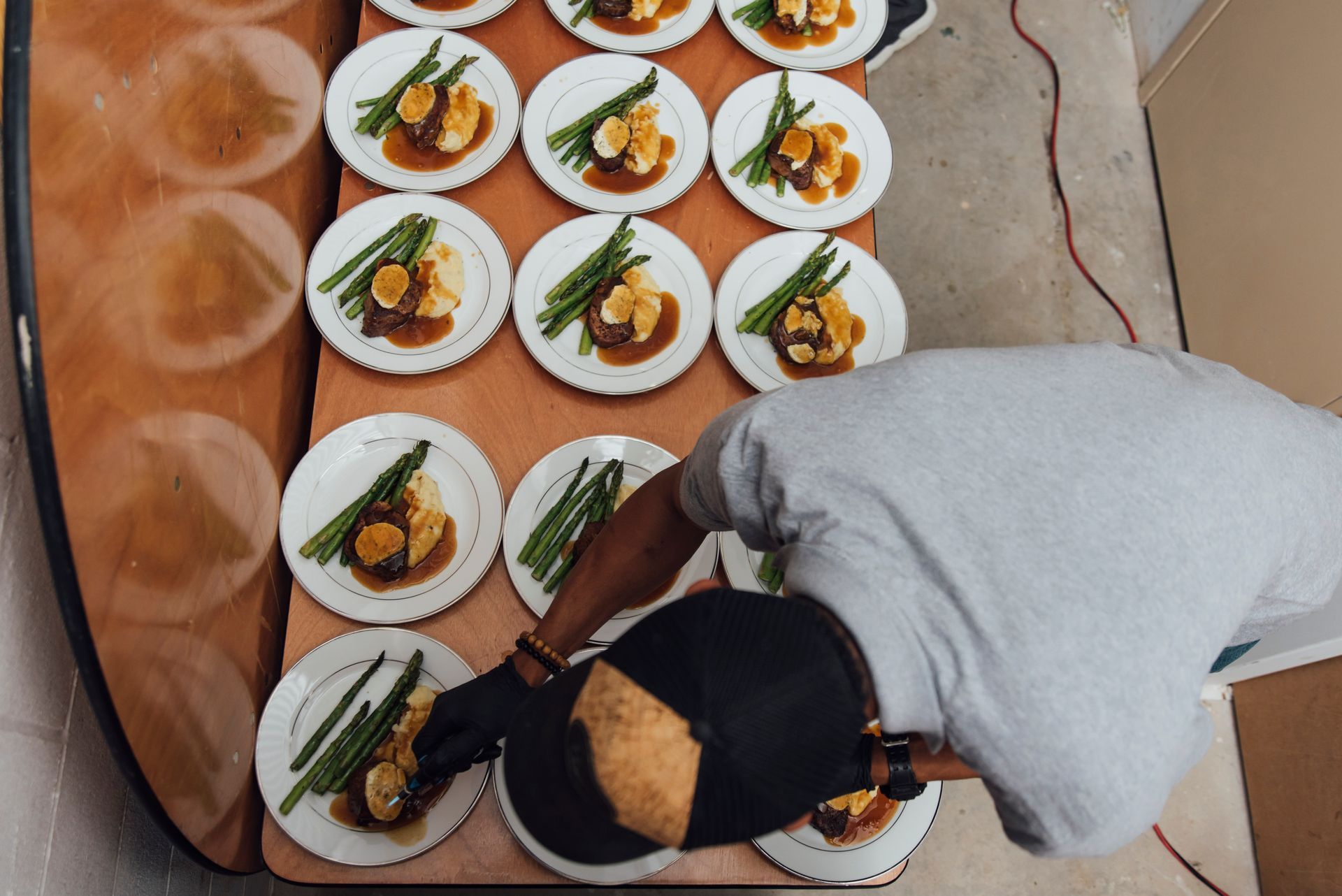 Person plating food on white plates with asparagus.