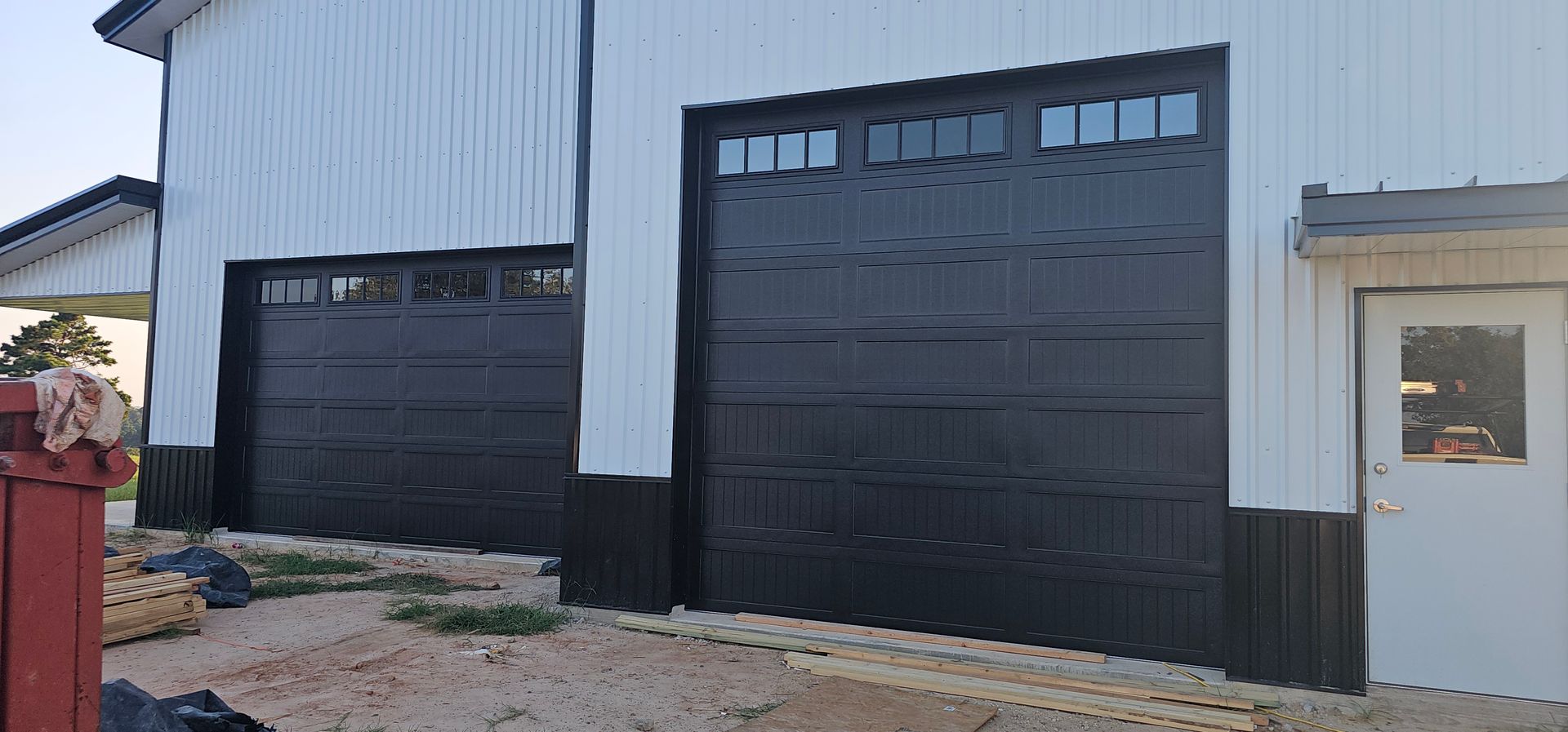 A white building with two black garage doors and a white door.