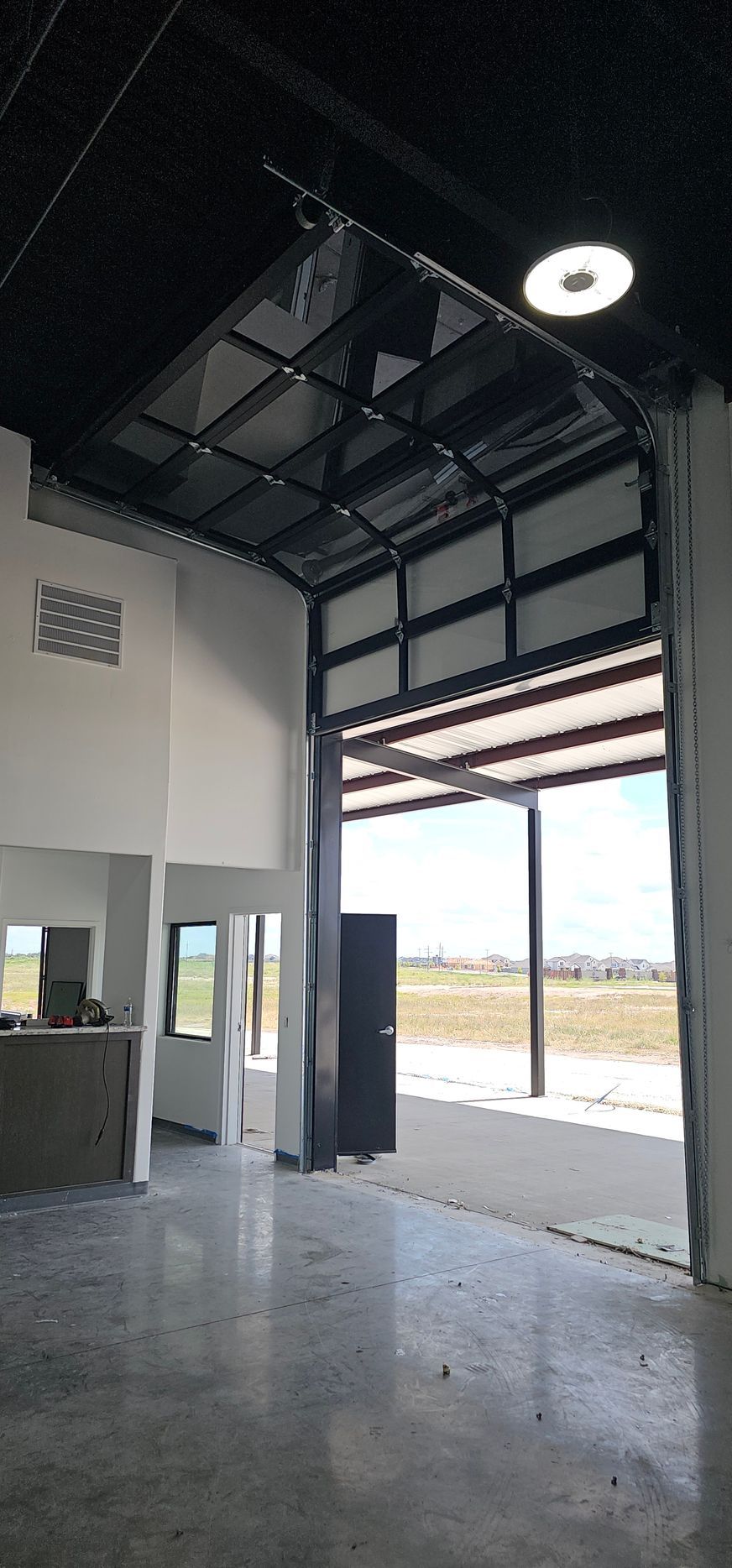A large empty warehouse with a large garage door open.