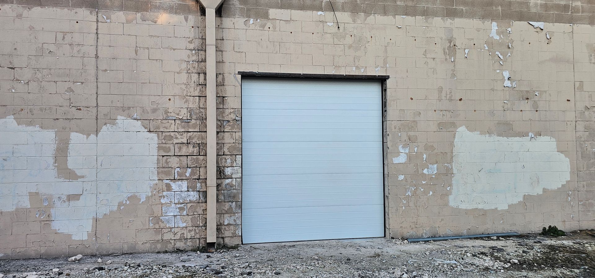 A white garage door is on the side of a brick building.