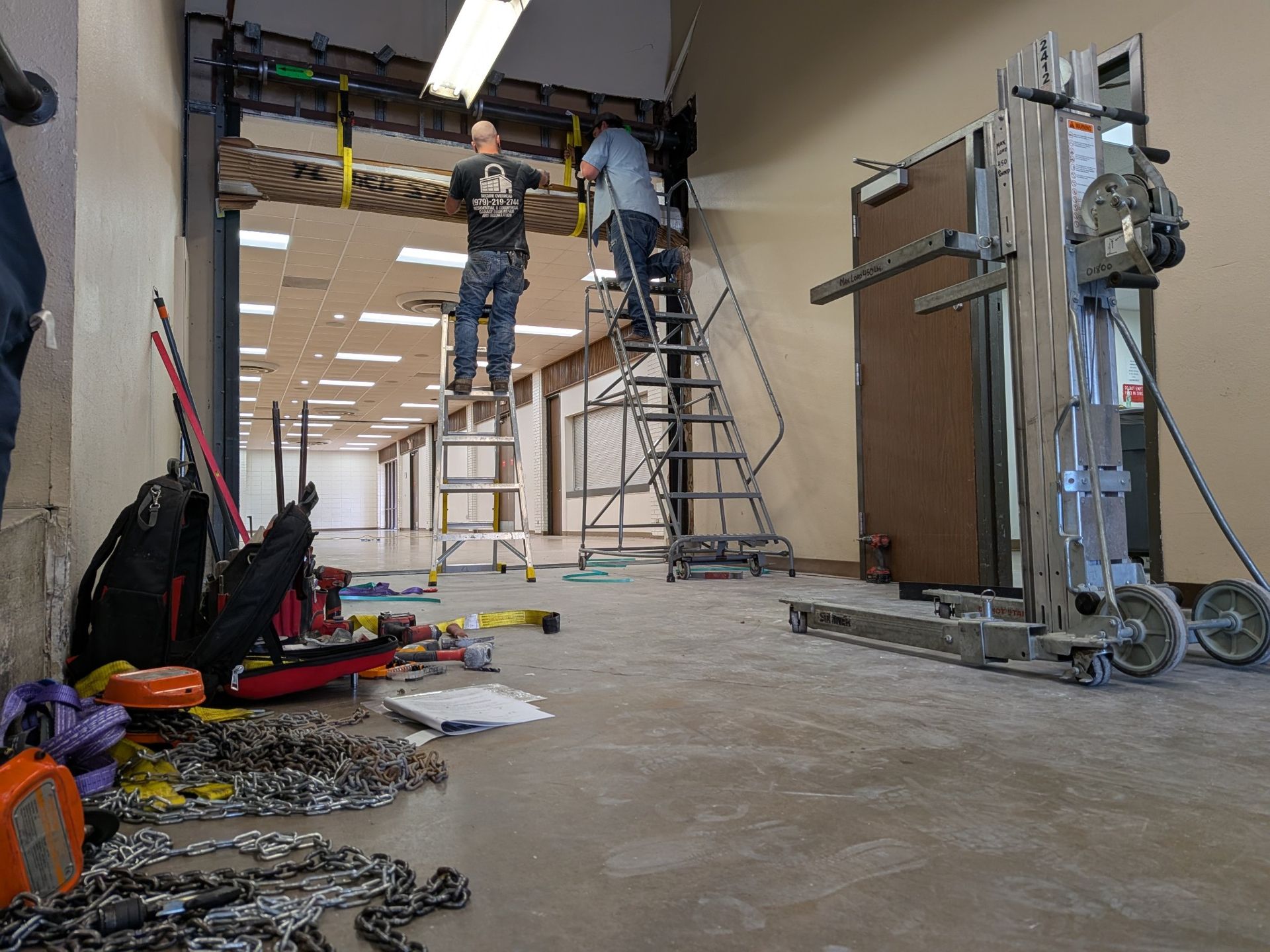 A man is standing on a ladder in an empty room.
