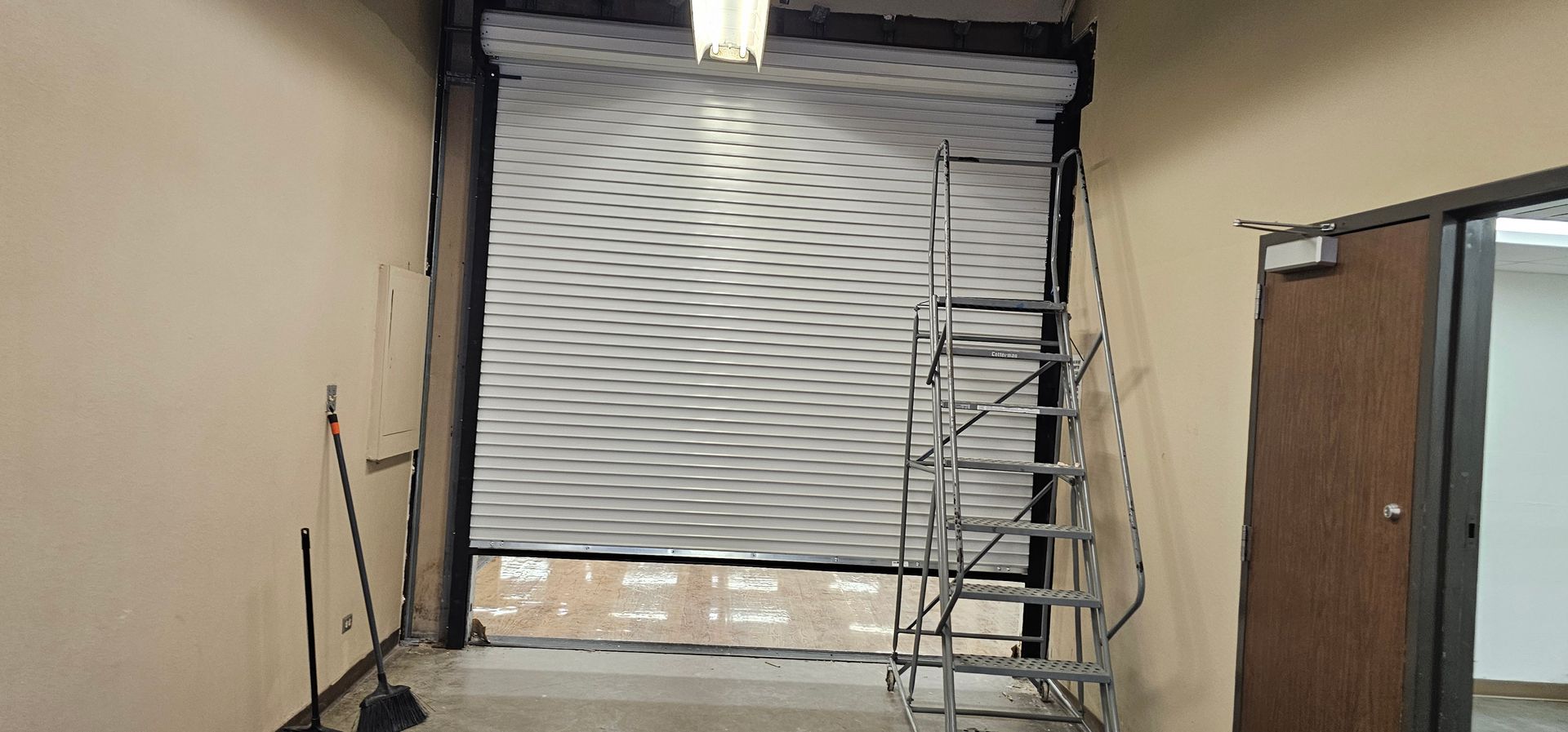 A room with a garage door and a ladder in it.